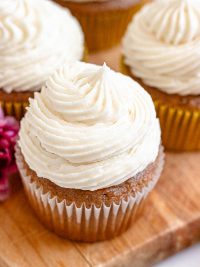 Cream cheese frosting piped over carrot cupcakes.