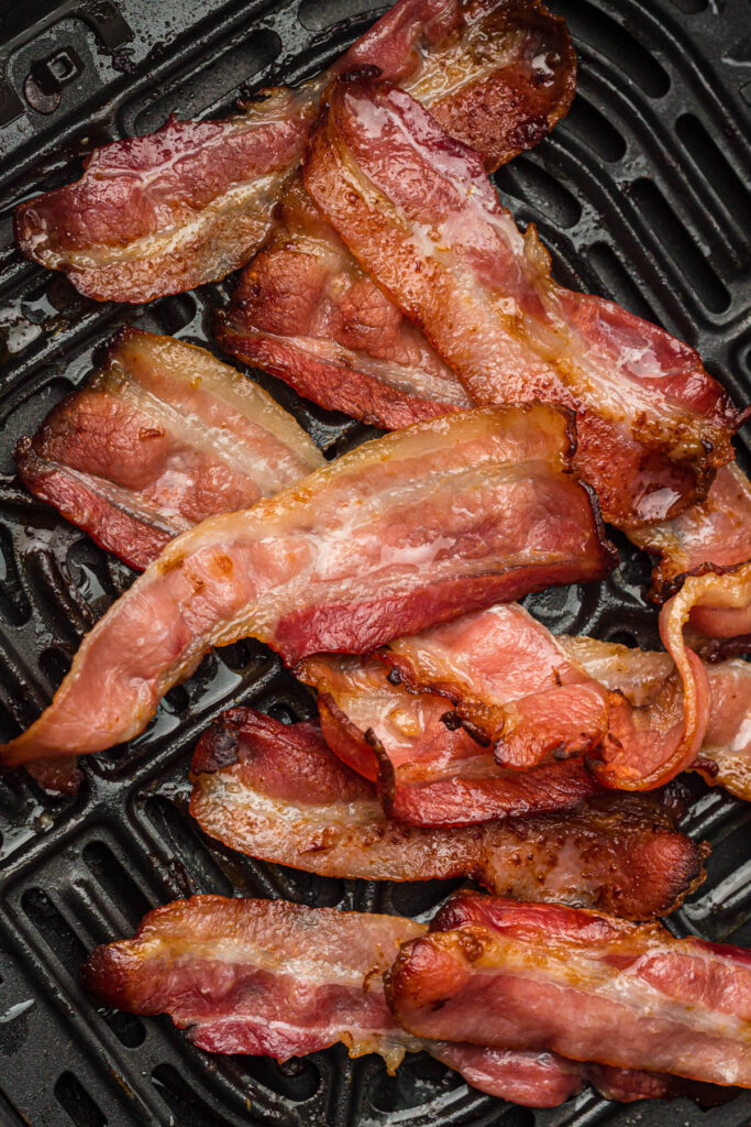 Bacon in the basket of an air fryer.